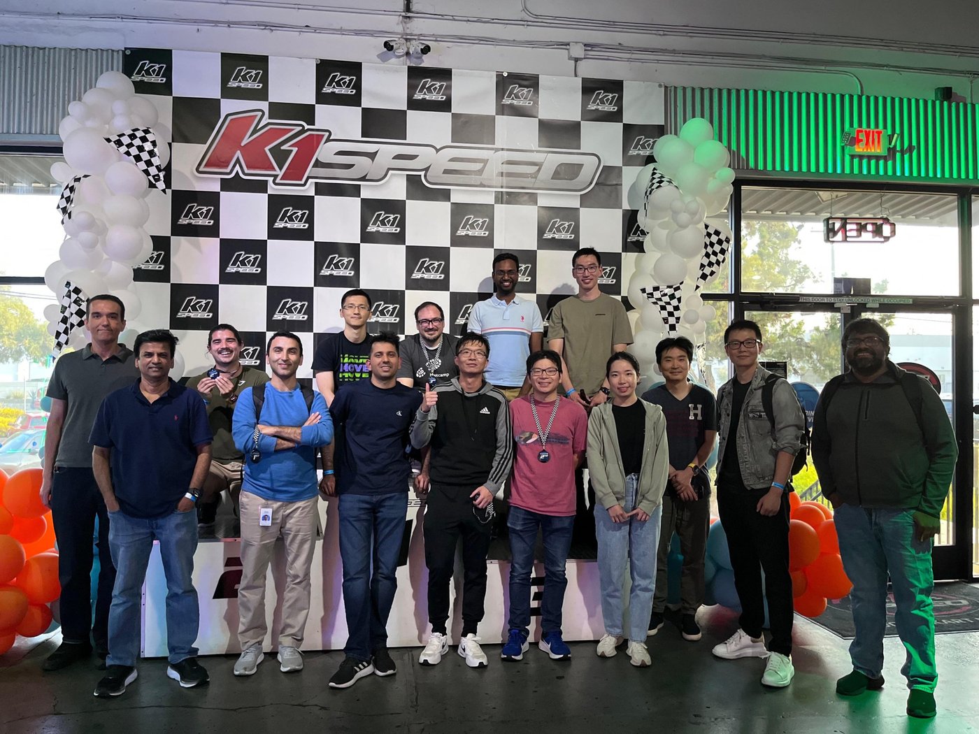 Fifteen colleagues in front of the K1 Speed checkered wall